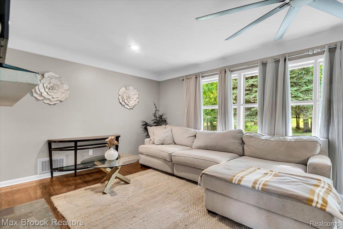 Living area featuring wood-finish flooring, recessed lighting, crown molding, and a large multi-pane window configuration