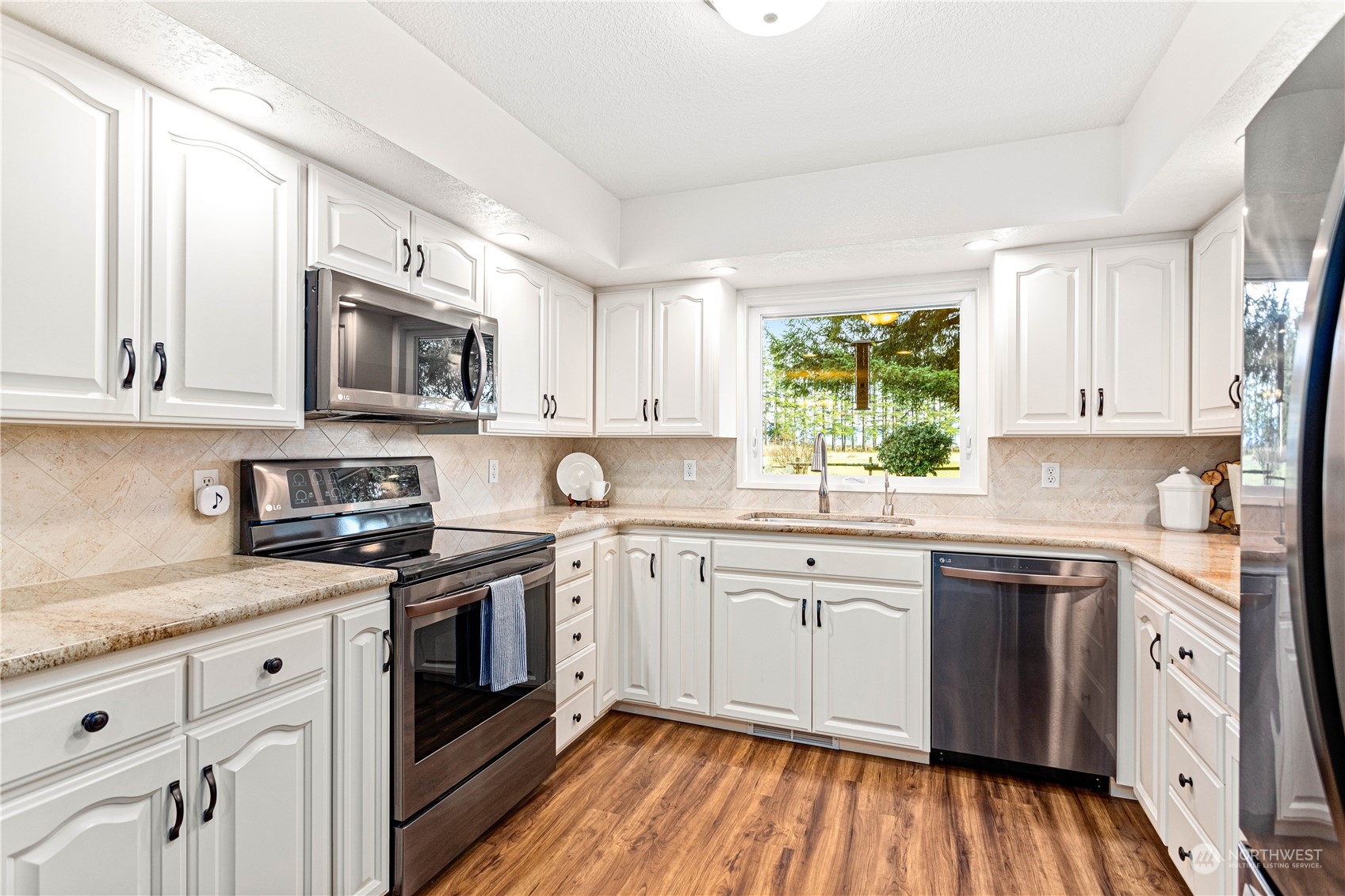 8669 Berthusen Road Lynden, WA 98264 - Photo 12 of 39 a kitchen with stainless steel appliances granite countertop white cabinets a sink dishwasher a stove and a refrigerator with wooden floor