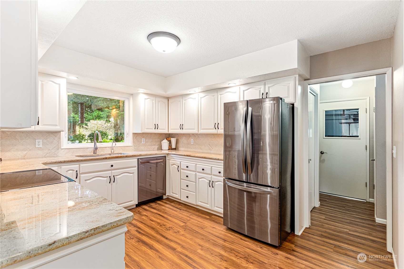 8669 Berthusen Road Lynden, WA 98264 - Photo 10 of 39 a kitchen with granite countertop stainless steel appliances a refrigerator cabinets and wooden floor