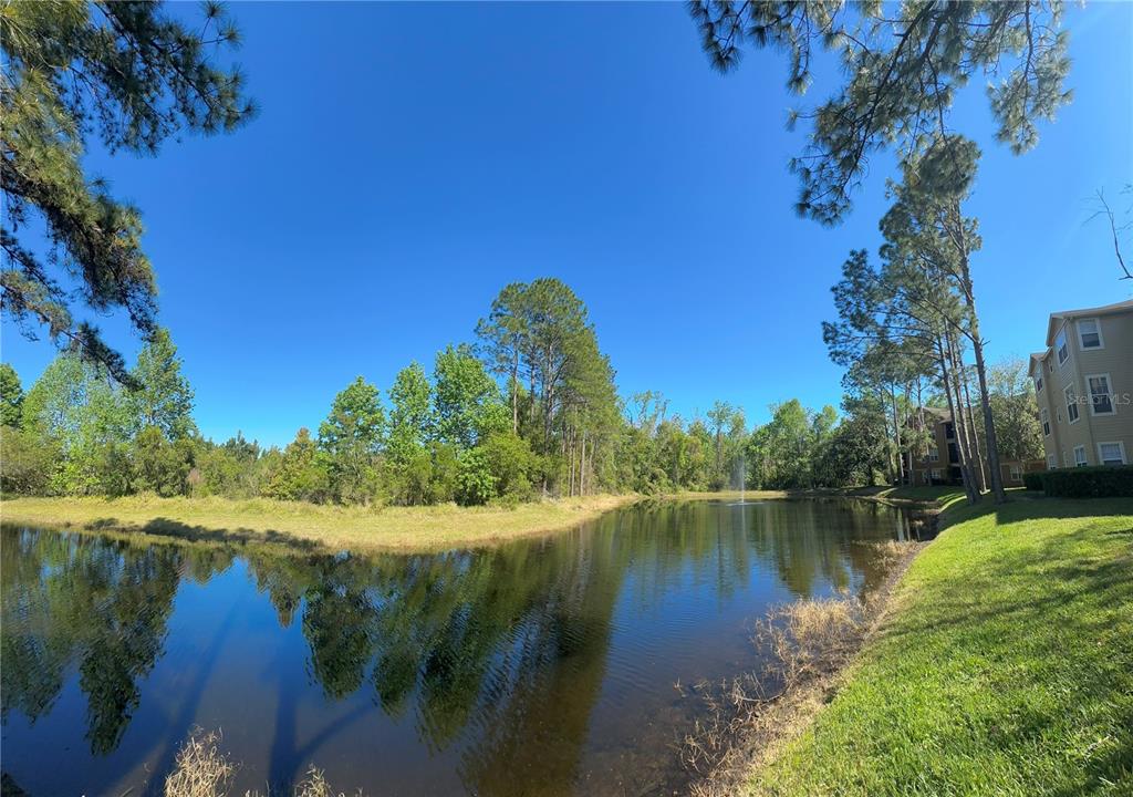 413 Summit Ridge Place, Unit 115 Longwood, FL 32779 - Photo 5 of 44 a view of a lake with a yard and large trees