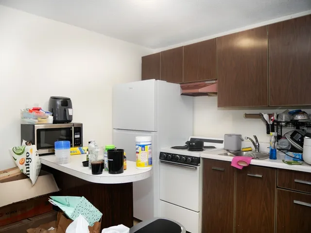 a room with a white cabinets a sink dishwasher and a stove with wooden floor