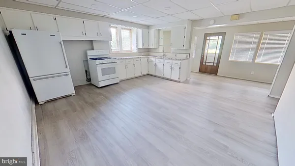 a kitchen with white cabinets and wooden floors