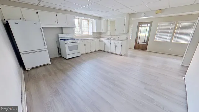 a kitchen with white cabinets and wooden floors