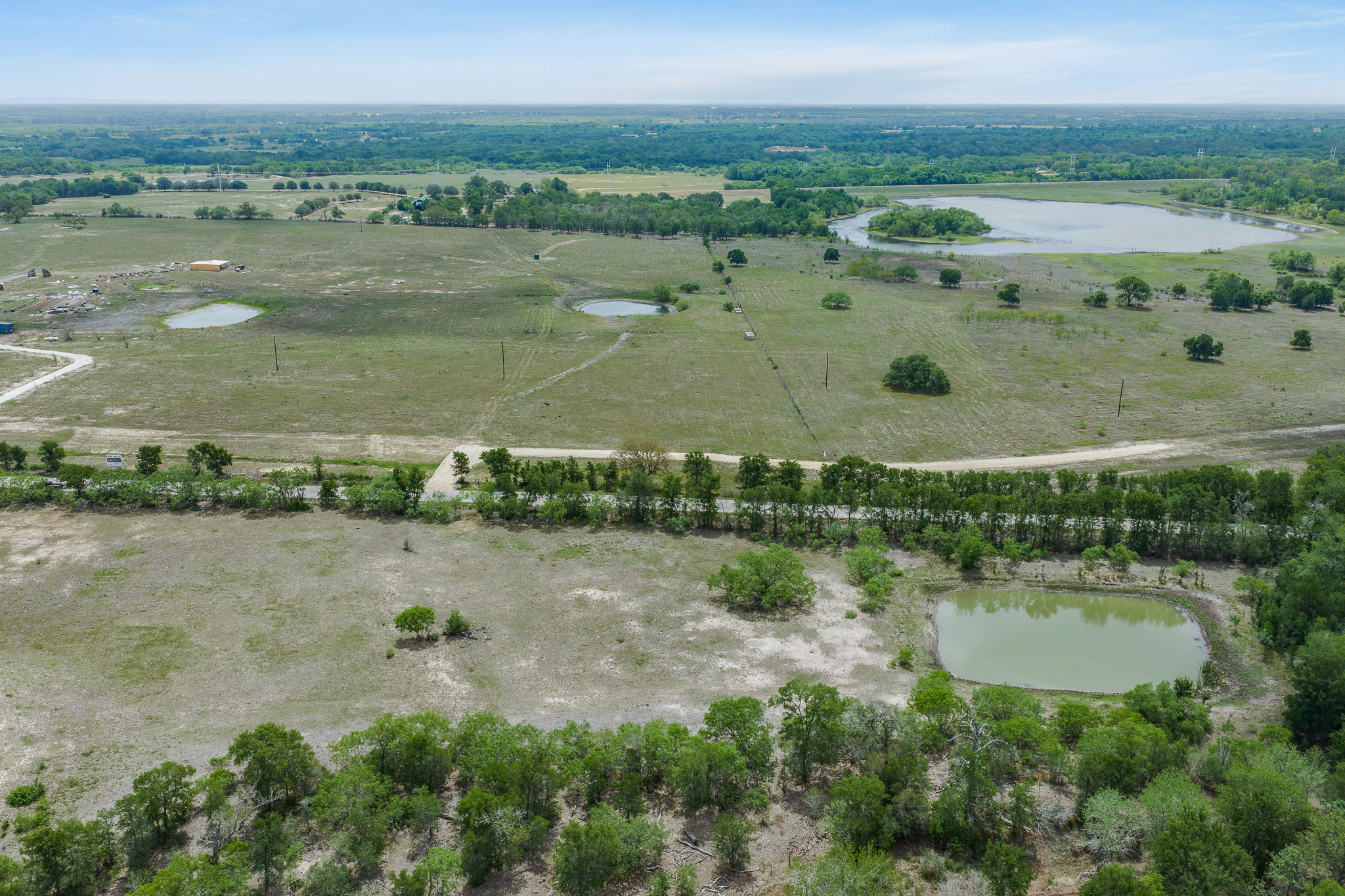 Lot 29 Mineral Springs Ranch Lockhart, TX 78644 - Photo 7 of 8 Vast, undeveloped acreage featuring multiple ponds and distant wooded areas, presenting a prime investment opportunity.