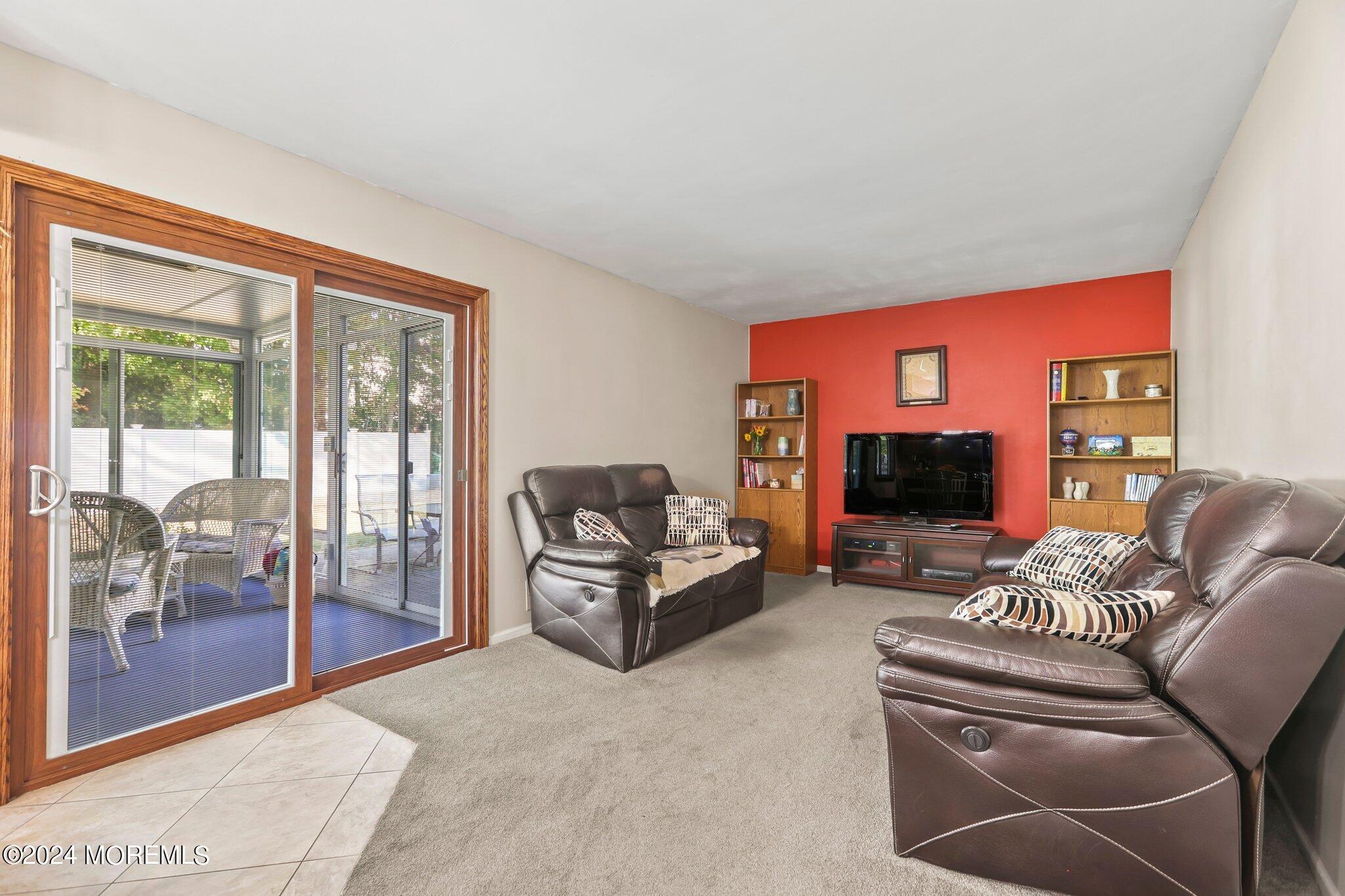 14 Cherry Bend Drive Howell, NJ 07731 - Photo 17 of 47 a living room with furniture a flat screen tv and a floor to ceiling window