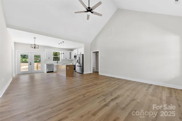 a view of a livingroom with wooden floor a ceiling fan and staircase
