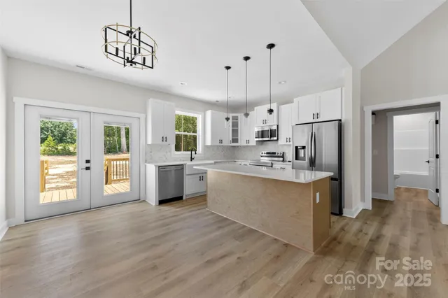 a large kitchen with stainless steel appliances kitchen island a large counter top and wooden floors