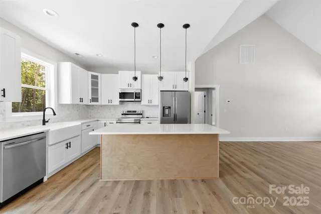 a large kitchen with kitchen island a sink stainless steel appliances and cabinets