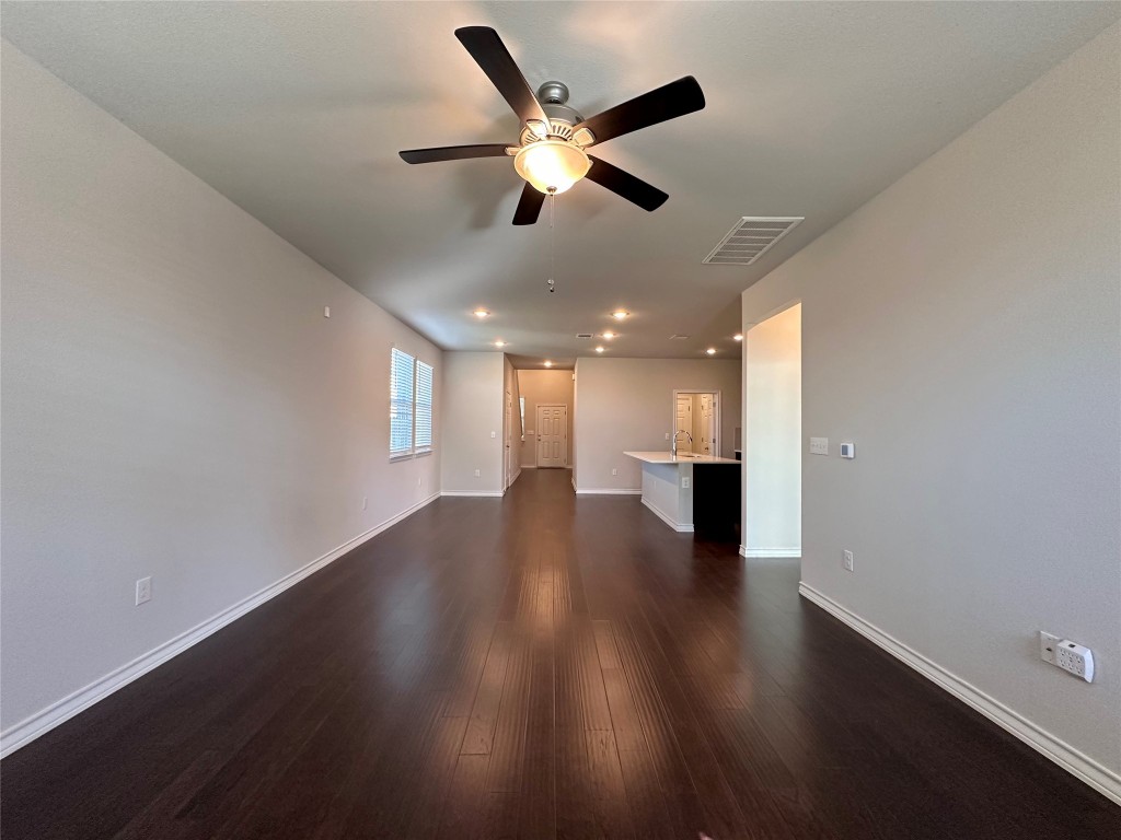 11604 Roxburgh Pass Manor, TX 78653 - Photo 20 of 40 a view of an empty room with wooden floor and a ceiling fan