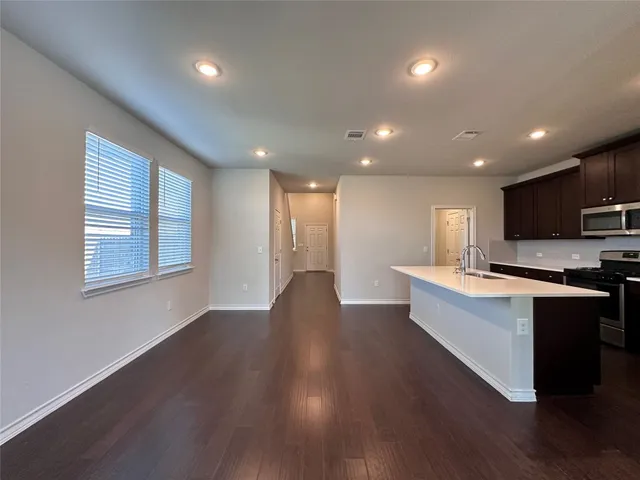 a view of an empty room with wooden floor and a ceiling fan