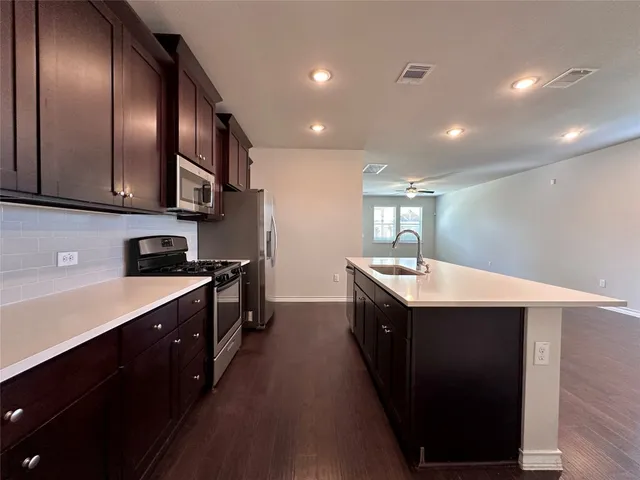 a large kitchen with stainless steel appliances lots of counter space and wooden floor