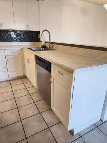 a kitchen with a sink a stove and white cabinets