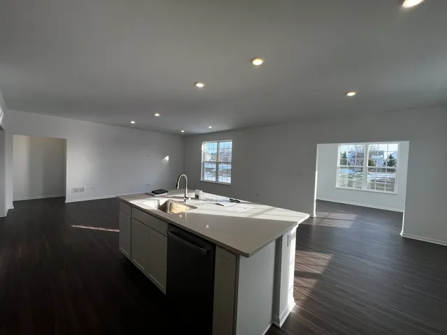 a kitchen with stainless steel appliances granite countertop a sink a stove a dining table and chairs with wooden floor