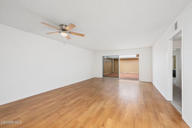 a view of empty room with wooden floor and ceiling fan