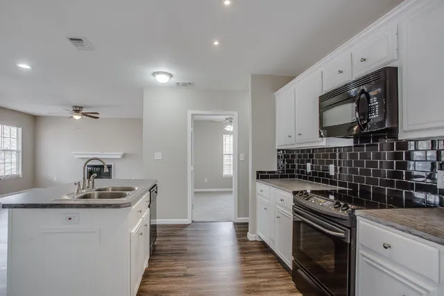 a kitchen with granite countertop a sink a stove and cabinets
