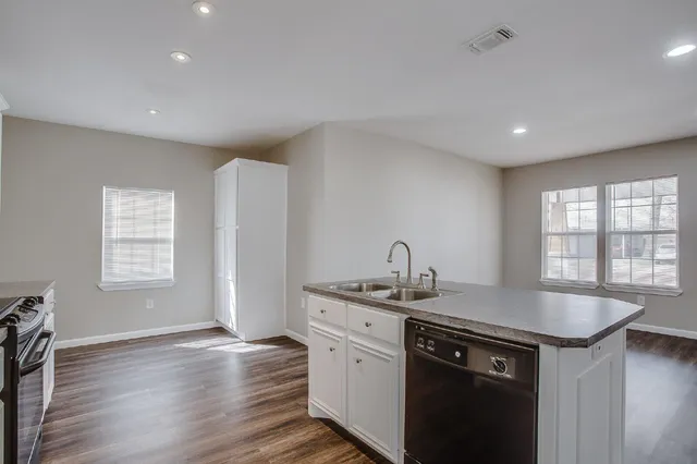 a kitchen with a sink cabinets and wooden floor
