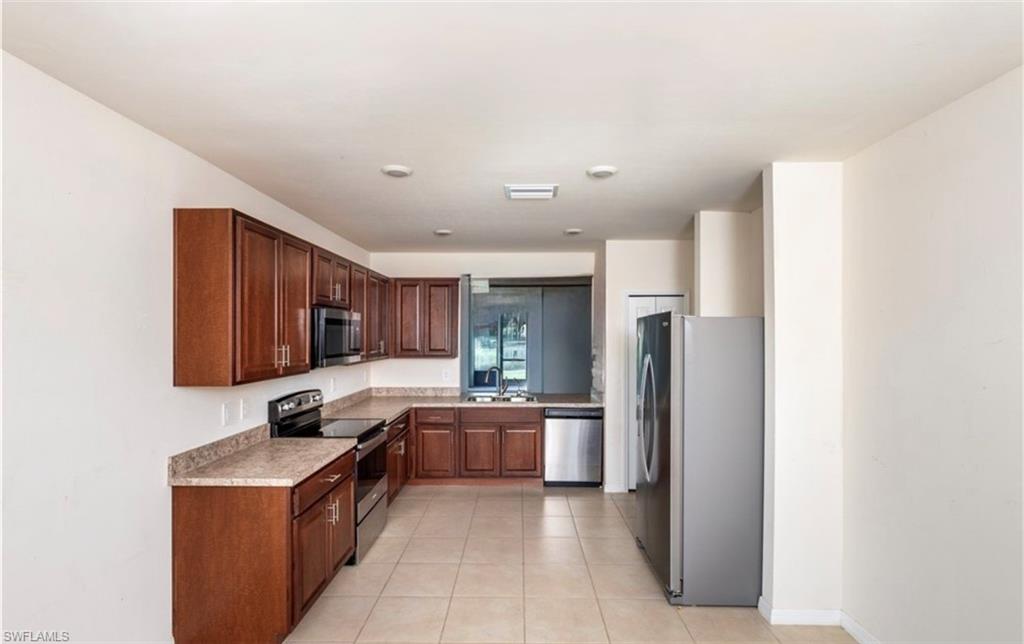 2802 40th Street Southwest Lehigh Acres, FL 33976 - Photo 3 of 14 Kitchen with stainless steel appliances, light countertops, and light tile patterned flooring