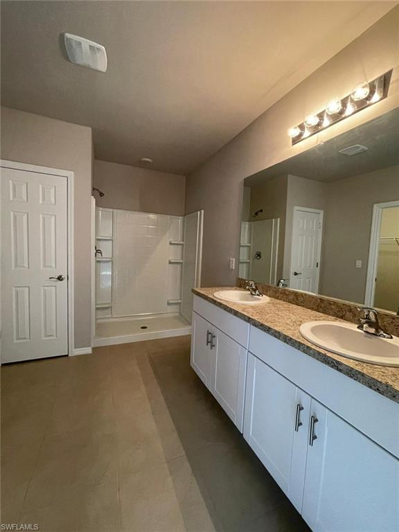 2802 40th Street Southwest Lehigh Acres, FL 33976 - Photo 6 of 14 Bathroom with a stall shower, double vanity, tile patterned floors, and a spacious closet