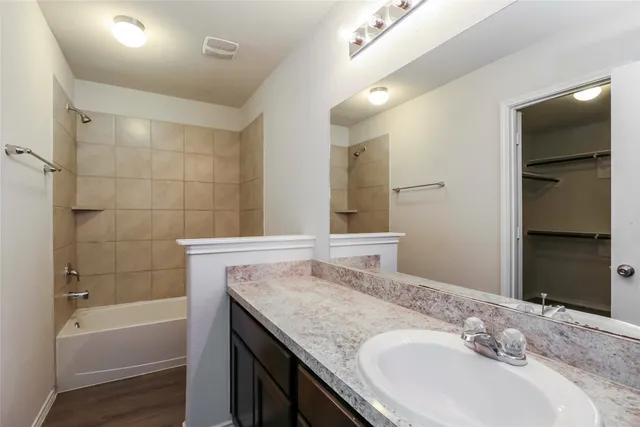 a bathroom with a granite countertop sink a mirror and a bathtub