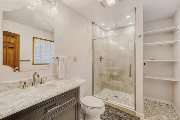 a bathroom with a granite countertop sink a toilet and shower