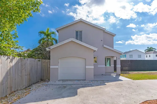 a view of a house with a yard and a large tree