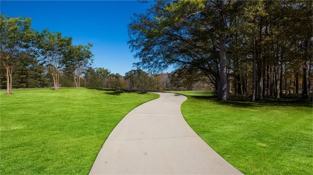 a view of a house with a big yard plants and large trees