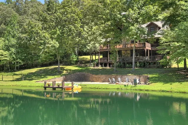 a view of a house with a large windows and a yard with plants and large trees
