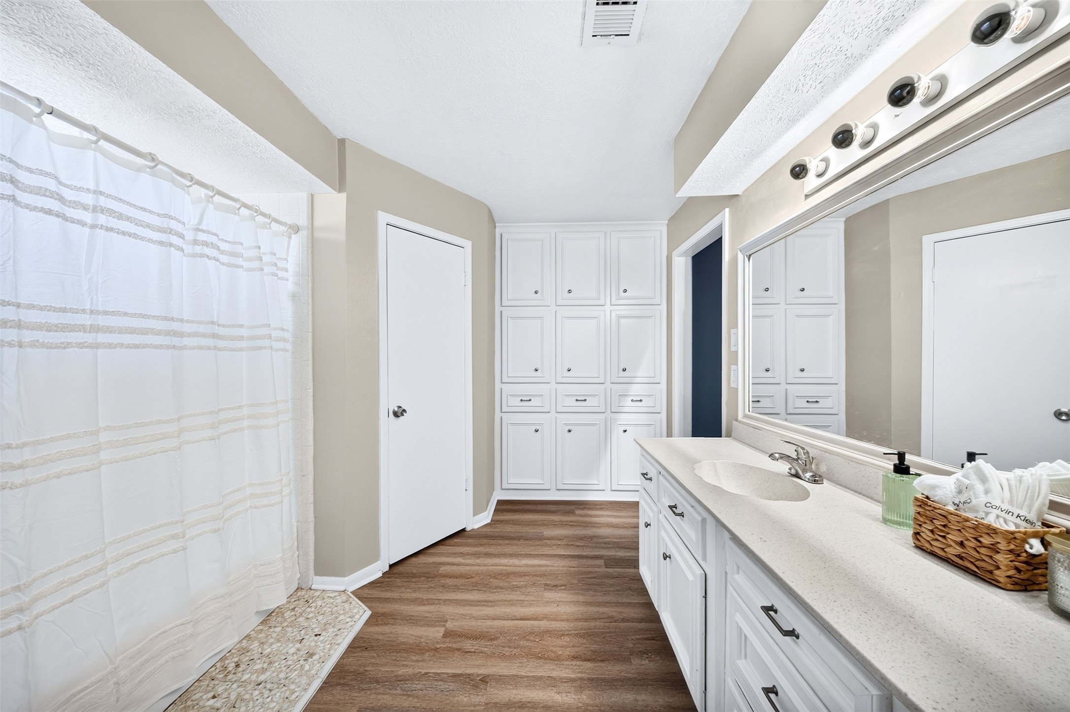 6507 Spring Leaf Drive Spring, TX 77379 - Photo 21 of 50 This primary bathroom features an oversized vanity with abundant countertop space, a large wall to all mirror, extensive built in cabinetry and lots of linen storage. Durable wood looking floor, and a combo shower/tub perfect for when on the go or a day of relaxing in the tub.
