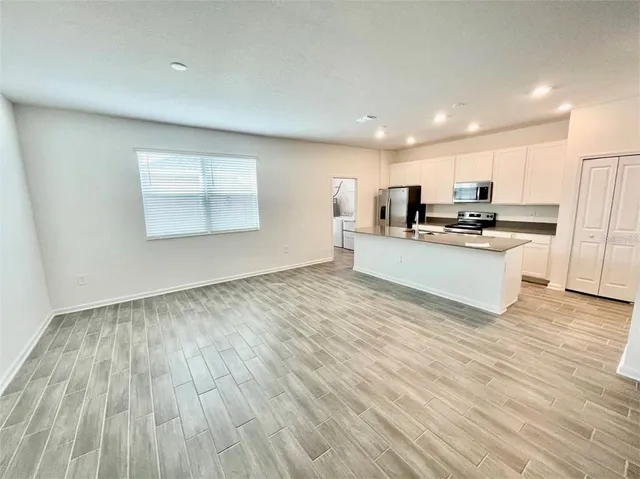 a large kitchen with a wooden floor and stainless steel appliances