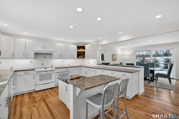 a kitchen with a stove a sink a counter top space and living room view