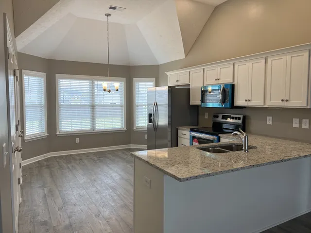 a kitchen with granite countertop a sink a counter top space cabinets and stainless steel appliances