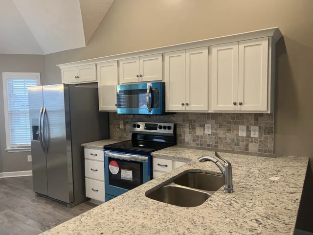 a kitchen with stainless steel appliances granite countertop a refrigerator sink and stove