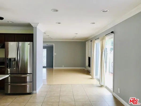 a view of a refrigerator in kitchen and an empty room