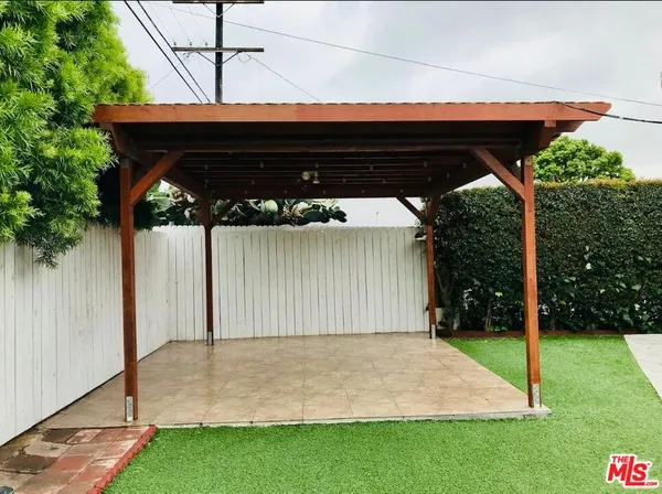 a backyard of a house with potted plants and palm trees
