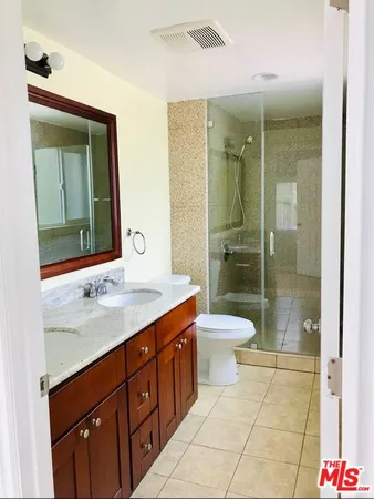a bathroom with a granite countertop sink toilet a mirror and shower