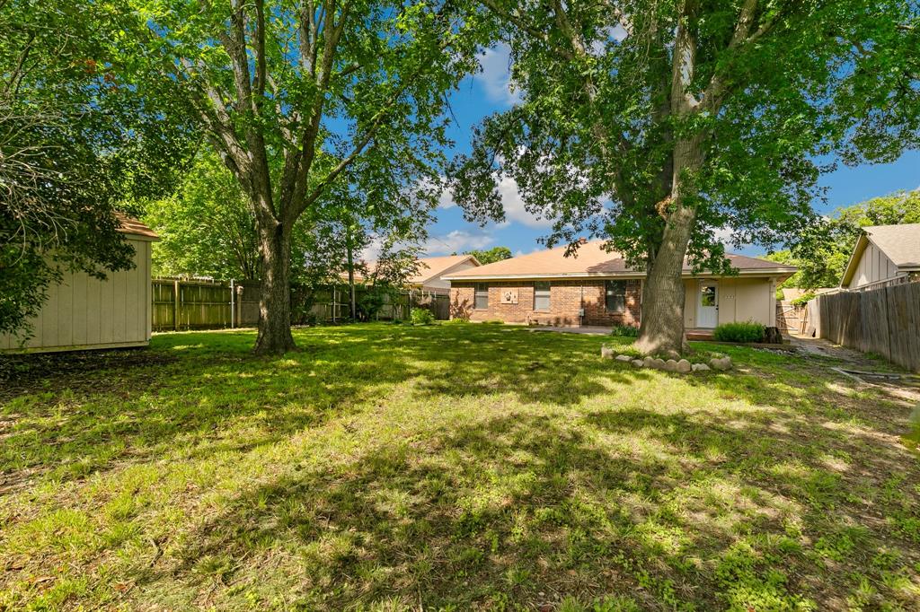 6612 Patsy Lane Watauga, TX 76148 - Photo 30 of 32 Expansive backyard featuring a large tree, a detached storage shed, and a privacy fence