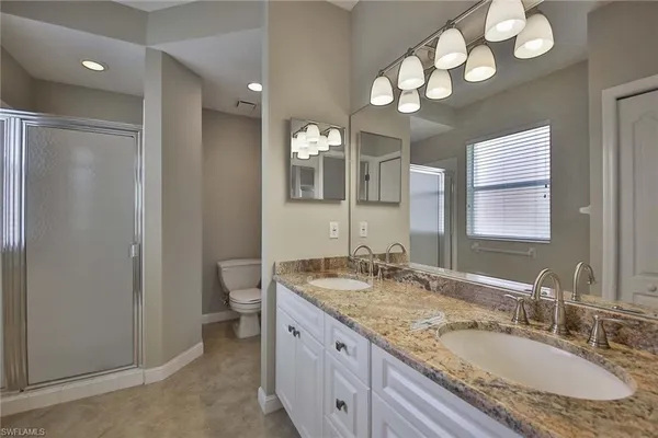 a bathroom with a granite countertop double vanity sink and a mirror
