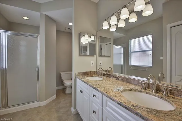 a bathroom with a granite countertop double vanity sink and a mirror
