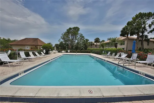 a view of a swimming pool with lawn chairs under an umbrella