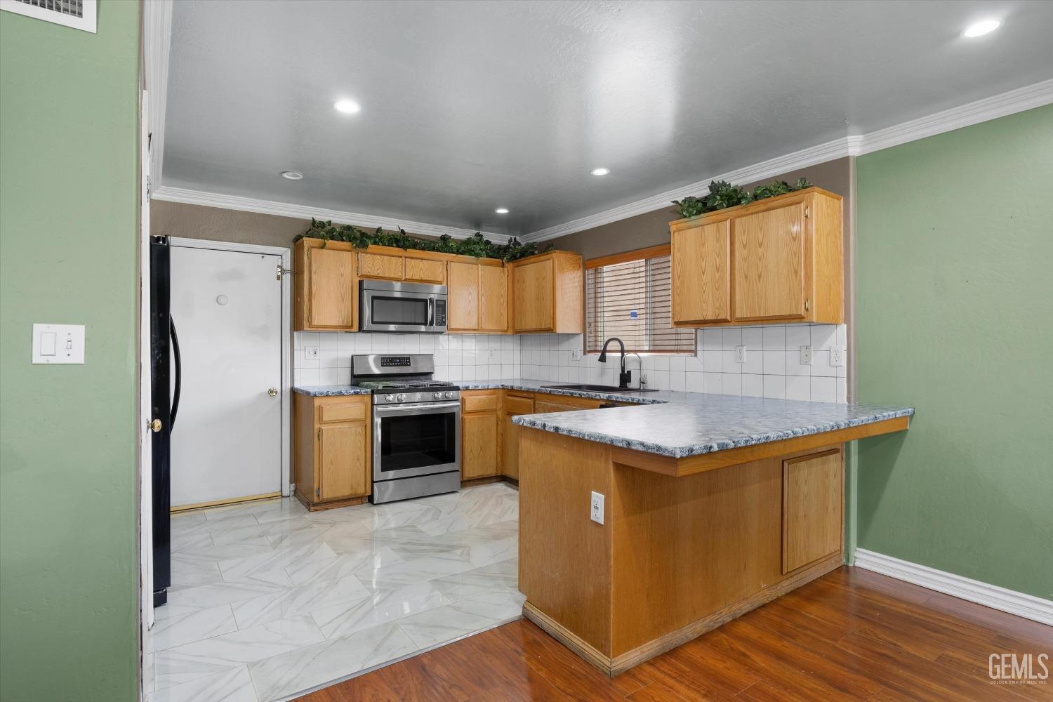 Undisclosed Address Bakersfield, CA 93313 - Photo 23 of 48 a kitchen with stainless steel appliances granite countertop a stove a sink dishwasher a refrigerator and a microwave oven with wooden floor