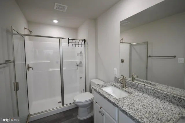 a bathroom with a granite countertop sink toilet and shower