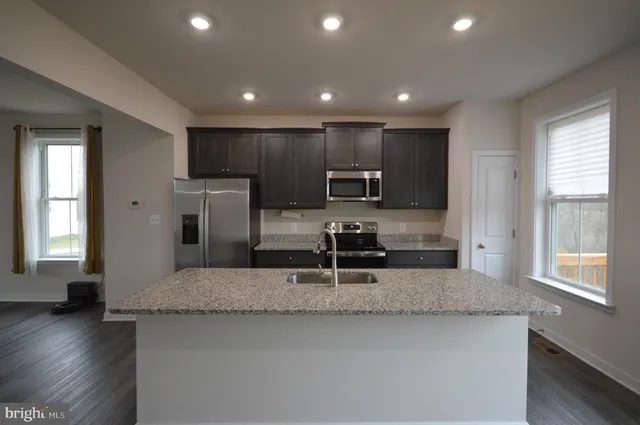 a kitchen with stainless steel appliances granite countertop a sink a stove and a refrigerator