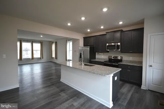 a large kitchen with stainless steel appliances granite countertop a large counter top a stove and a wooden floors
