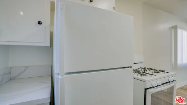 a kitchen with white cabinets and appliances