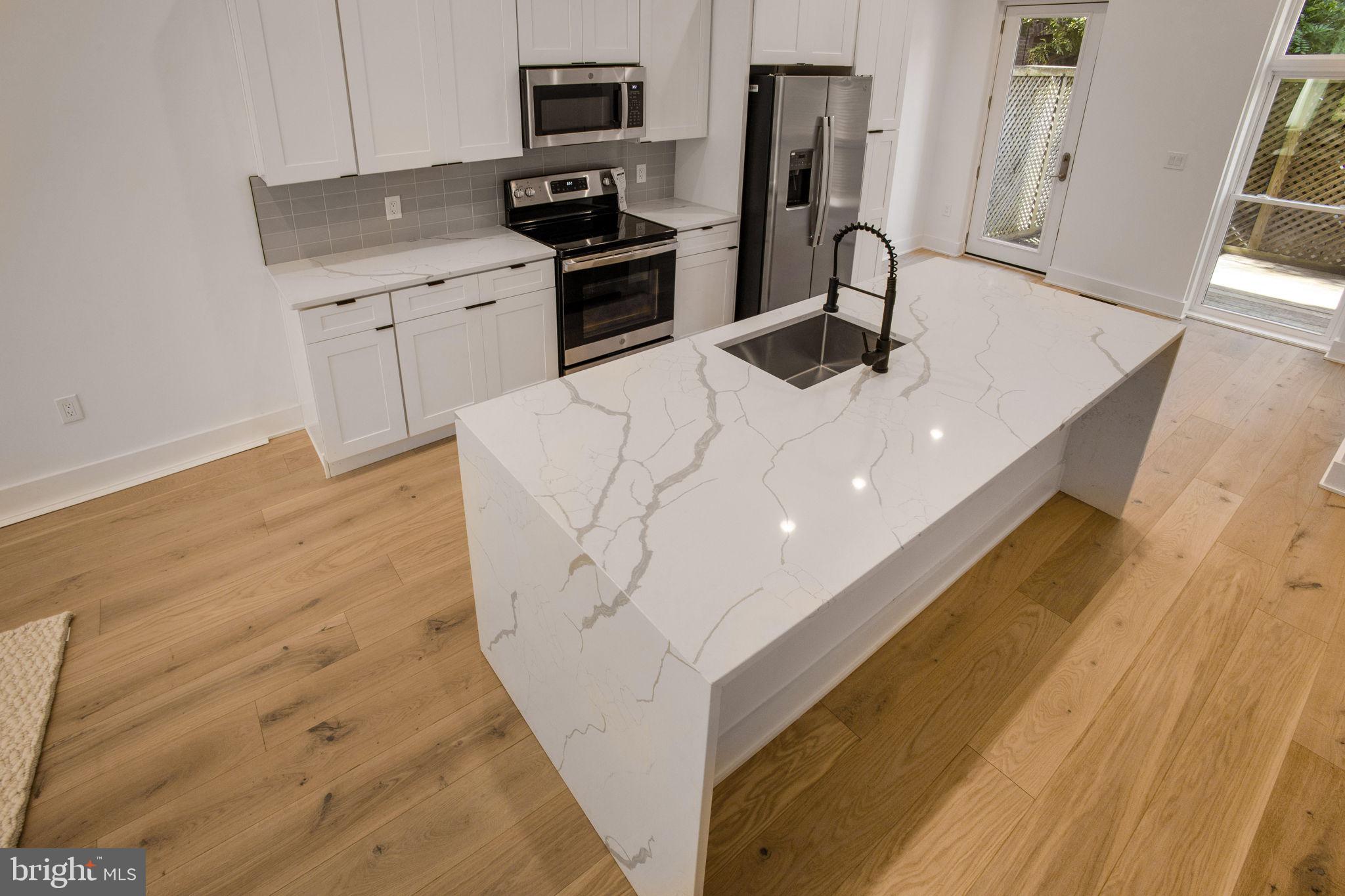 1211 Rhode Island Avenue Northwest, Unit 1 Washington, DC 20005 - Photo 8 of 24 a kitchen with stainless steel appliances kitchen island granite countertop a sink and a stove