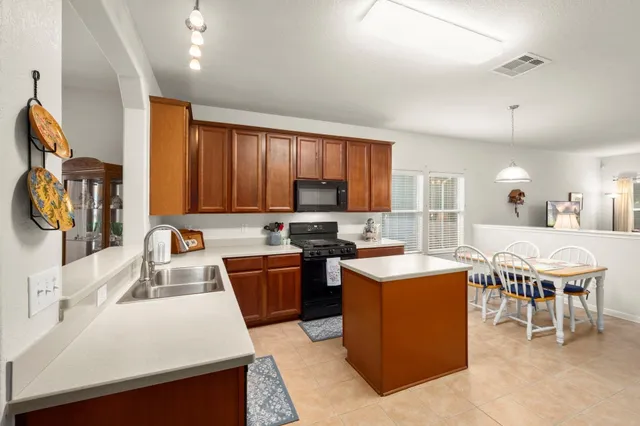 a living room with stainless steel appliances kitchen island granite countertop a table chairs and a refrigerator