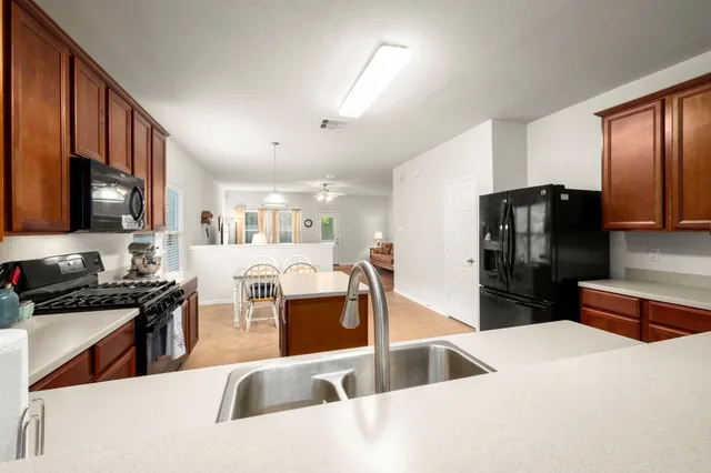 a kitchen with stainless steel appliances kitchen island granite countertop a refrigerator and a sink