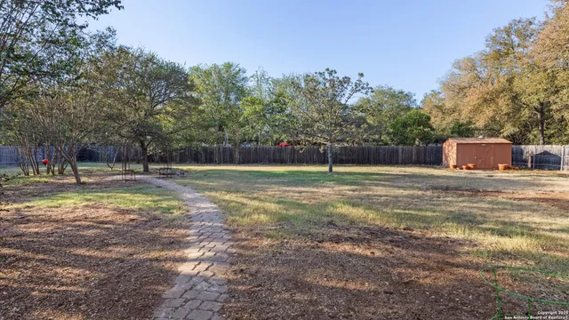 a view of a backyard with a small cabin and wooden fence