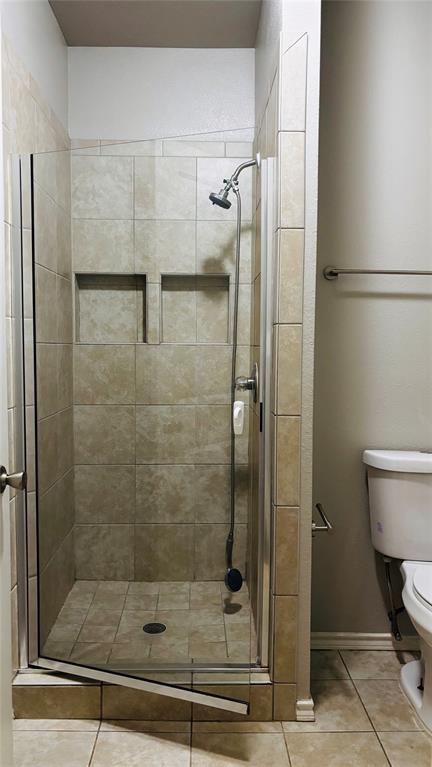 4511 Junius Street Dallas, TX 75246 - Photo 11 of 16 Bathroom 2 walk-in shower featuring glass enclosure, tiled walls and floor, dual recessed niches, and a handheld shower fixture