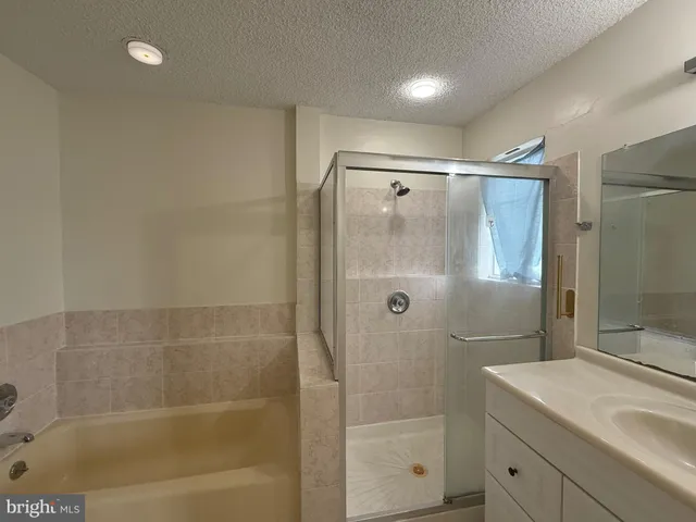 a kitchen with granite countertop a refrigerator a sink and white cabinets
